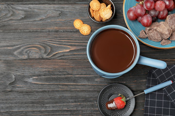 Flat lay composition with chocolate fondue and space for text on dark wooden background