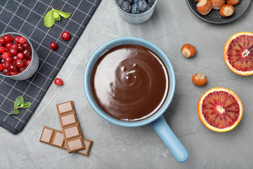Flat lay composition with chocolate fondue on grey stone background