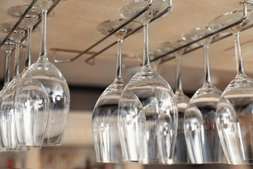Set of empty clean glasses on bar racks