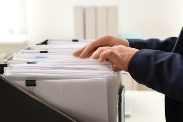 Woman taking documents from folder in archive, closeup