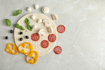 Flat lay composition with base and ingredients for pizza on marble table, space for text
