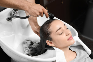 Naklejka premium Stylist washing client's hair at sink in beauty salon