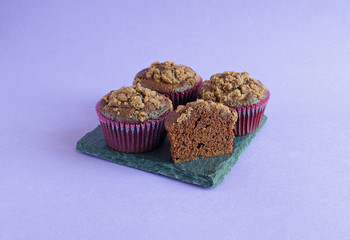 Set of chocolate muffins on black square board on purple background