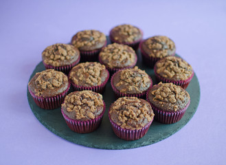 Set of chocolate muffins on black round board on purple background