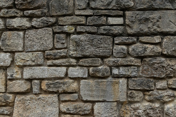 Alte Natursteinmauer aus grauen und gelblichen Steinen in unterschiedlichen Größen