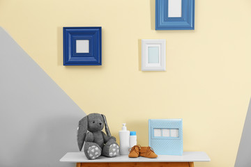 Toy and child accessories for baby room interior on table near color wall