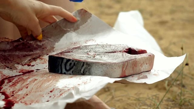 Close-up shot of female hand salting a fillet of tuna fish. Slow motion. HD