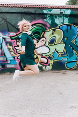 Obraz premium Young cheerful blondie woman listening to music, chating, listening audio in earphones, doing selfie outdoors in green summer park. Technology, communication, music, leisure concept