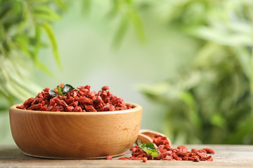 Bowl of dried goji berries on table against blurred background. Space for text