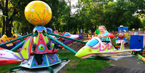 Pretty little girl rides a carousel in an amusement Park in the summer.