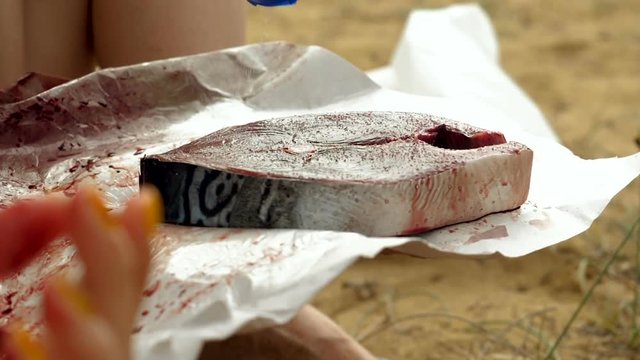 Close-up shot of female hand peppering a fillet of tuna fish. Slow motion. HD