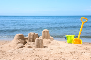 Fototapeta na wymiar Little sand figures and plastic toys on beach near sea