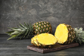 Board with cut fresh juicy pineapple on wooden table, space for text