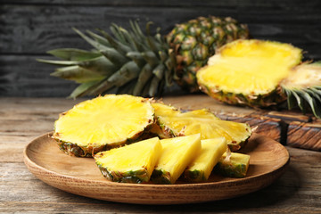 Tray with cut fresh juicy pineapple on wooden table