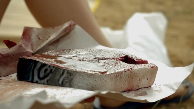 Close-up shot of female hand rubbing olive oil to a fillet of tuna fish. Slow motion. HD