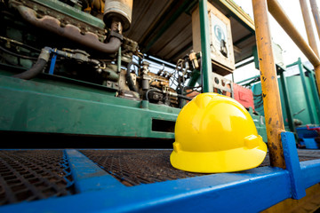 Yellow hardhat or safety helmet is placed on working platform of pumping unit in oil field...