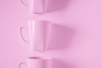 Pink coffee mugs on pink background in a vertical row with empty copyspace