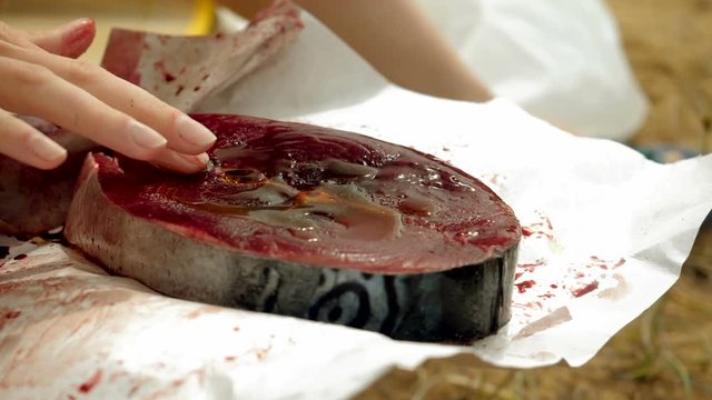 Close-up shot of female hand rubbing olive oil to a fillet of tuna fish. Slow motion. HD
