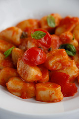 close up of Gnocchi with cherry tomatoes and basil isolated on a white plate and white background