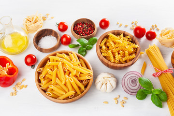 assorted raw pasta flat lay on white. spaghetti fusilli penne tagliatelle girandole