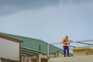 Fototapeta premium Worker welding the steel part for roof before it is going to rain.