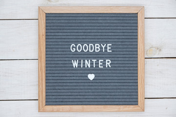 English text goodbye winter on a letter Board in white letters on a gray background and a symbol of heart