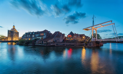 The center of Enkhuizen in the Netherlands with the old city gate - Drommedaris in the background, during the blue hour - dusk..