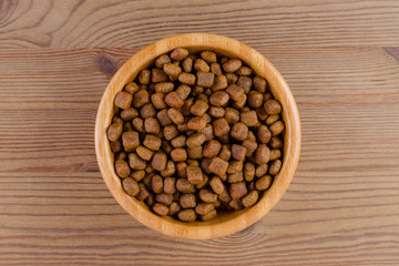 Fototapeta na wymiar dog food in a bowl on wooden background, flat lay