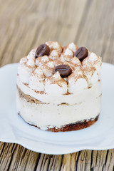 Coffee tiramisu cake on a white plate. Delicious beautiful festive dessert side view