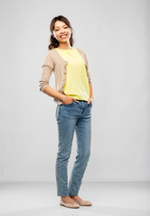 people, ethnicity and portrait concept - happy asian young woman over grey background