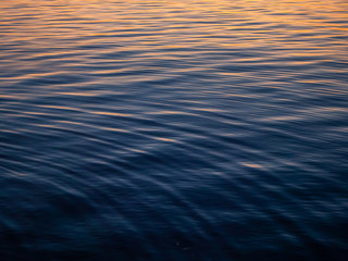 The texture of the water at sunset with sun reflections