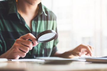 Man looking through a magnifying glass to documents. Business assessment and audit. Magnifying...
