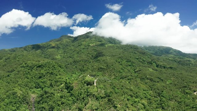 Aerial drone view of clouds moving over the slopes of the volcano Mount Mambajo on Camiguin island