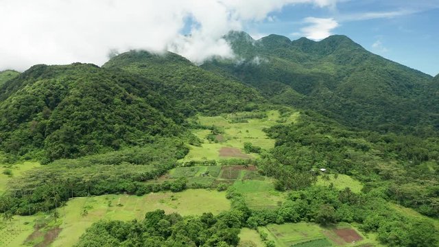 Aerial drone view of clouds moving across the slopes of Mount Hibok-Hibok volcano with lush green farmland below (Camiguin, Philippines)
