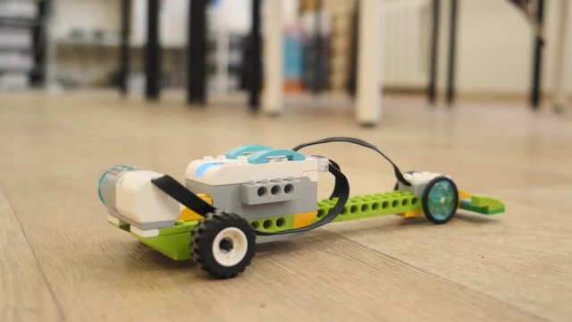 Mini model of plastic electronic car moves dow the floor close up view slow motion