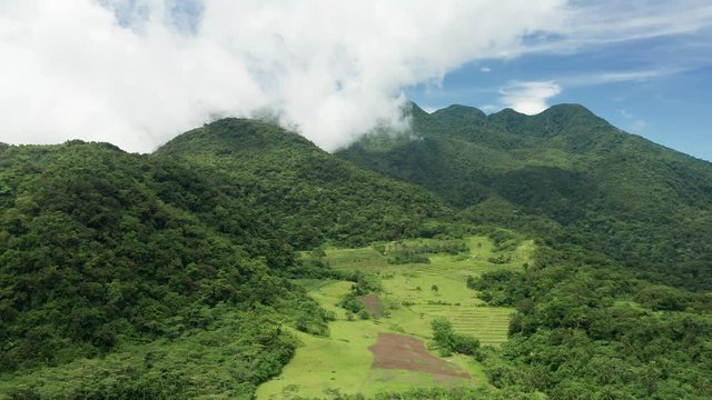 Aerial drone view of clouds moving across the slopes of Mount Hibok-Hibok volcano with lush green farmland below (Camiguin, Philippines)