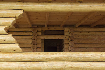 Gazebo made of logs. Window in wooden terrace. Elements of wooden construction.
