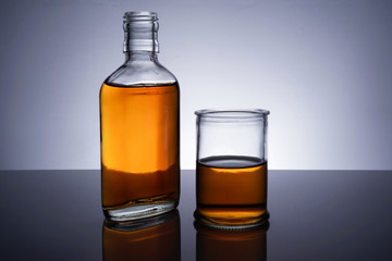 Obraz na płótnie Canvas A backlit of a glass bottle and jar with golden liquid 
