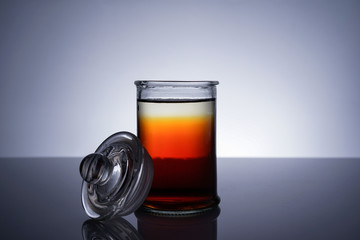 A jar with golden liquid on white background