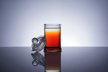 A jar with golden liquid on white background