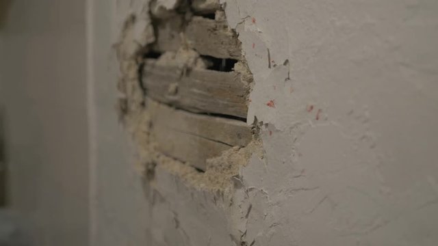 Fists punching plastered wall real time. CLOSE UP.