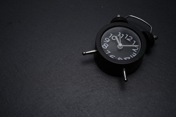 A black retro clock on black background