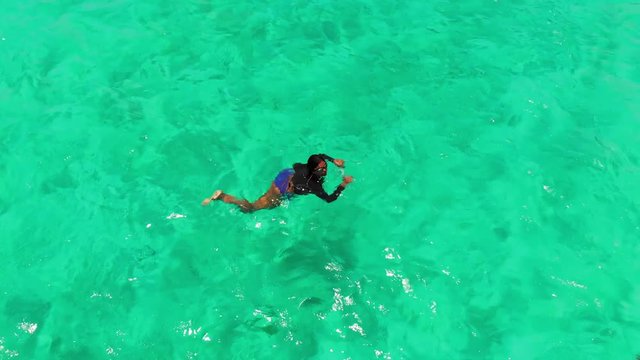 Aerial view of a model swimming in the crystal clear waters of Tobago Cays, St Vincent