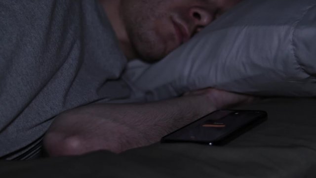 Man Waking Up in Bed to His Smartphone Alarm