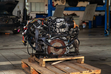 Replacement engine used on a pallet mounted for installation on a car after a breakdown and repair in a car repair workshop as a guarantee for the dealership. Auto service industry.