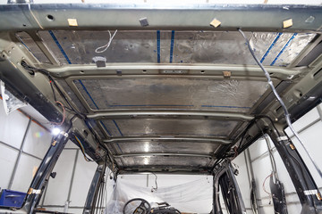 Tuning the car in a van bus body with three layers of noise insulation on the metal roof. Sound and vibration isolation using soft and rubber material with a car breakdown. Auto service undustry.