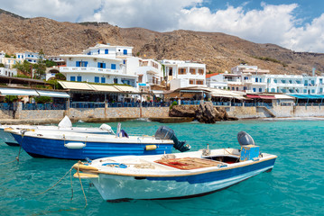 Fototapeta na wymiar Small moored fishing boats in blue lagoon of Crete island.