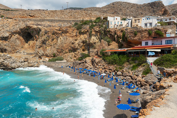 Fototapeta premium Beautiful blue lagoon with umbrellas at sandy beach, Chora Sfakion town, Crete island