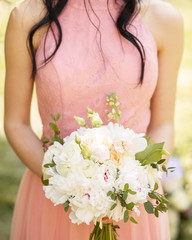 Modern bouquet of different flowers and green leaf. Beautiful wedding bouquet in bride's hands. 