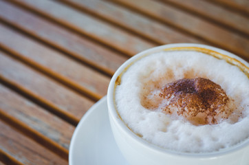 close up modern hot black coffee the cappuccino on wood background with coffee bubble foam pattern and texture in white cup looking and feel so delicious on glasses table in coffee shop.
